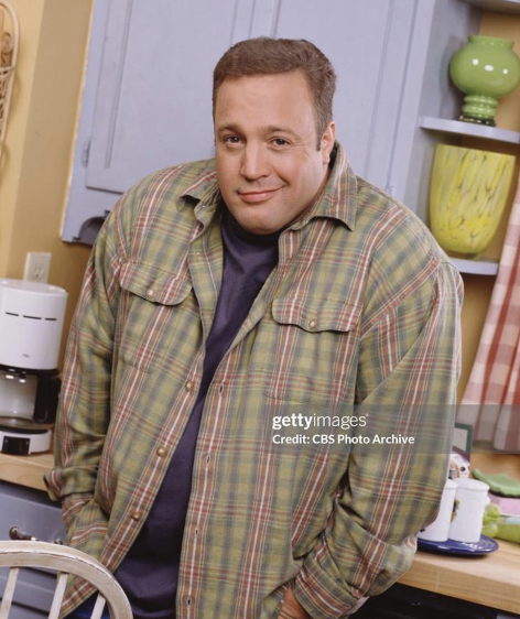 Kevin James with his hands in his pockets, shrugging and looking smug at the camera. 